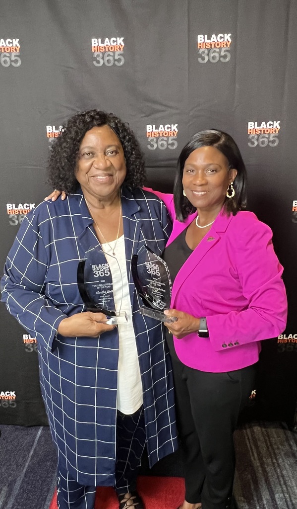 two black woman standing holding awards